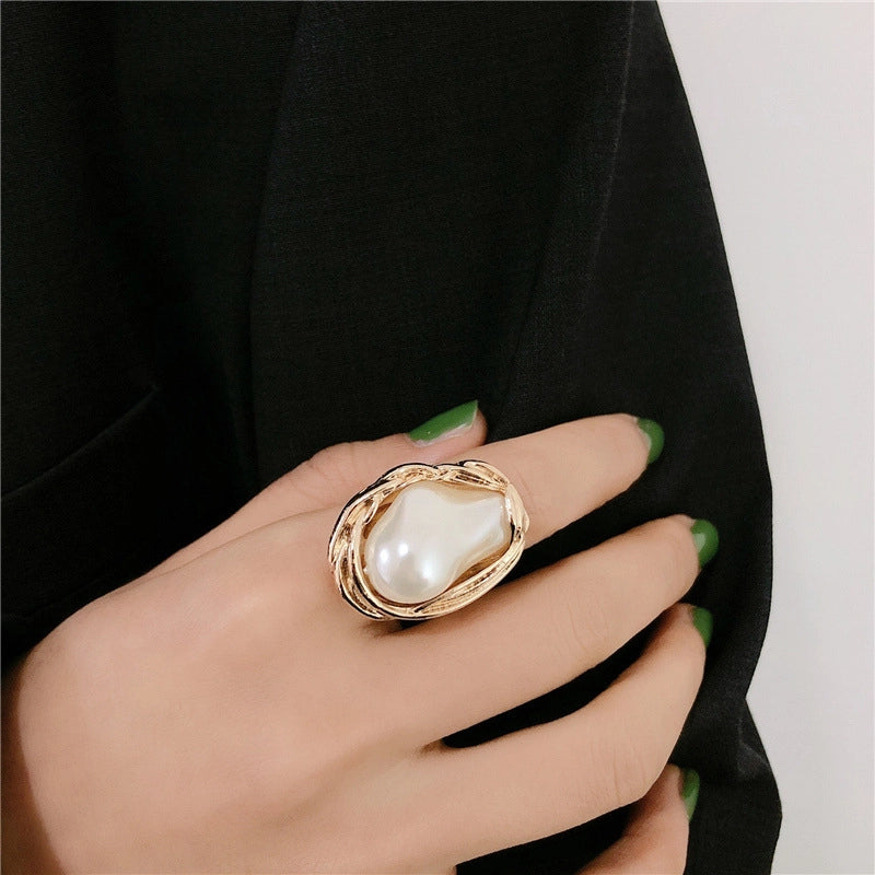 Un anello metallico unico ed esagerato, con un'apertura semplice e dalla forma irregolare e una perla incastonata sull'indice.