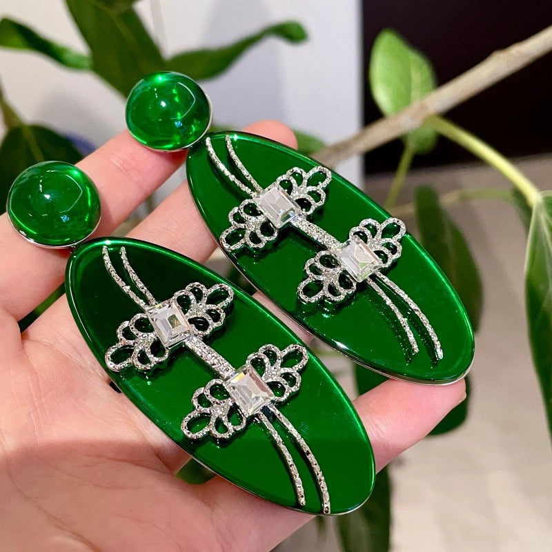 Orecchini ovali con smeraldo, chiusura a fiocco e fermaglio a cinque foglie in argento.