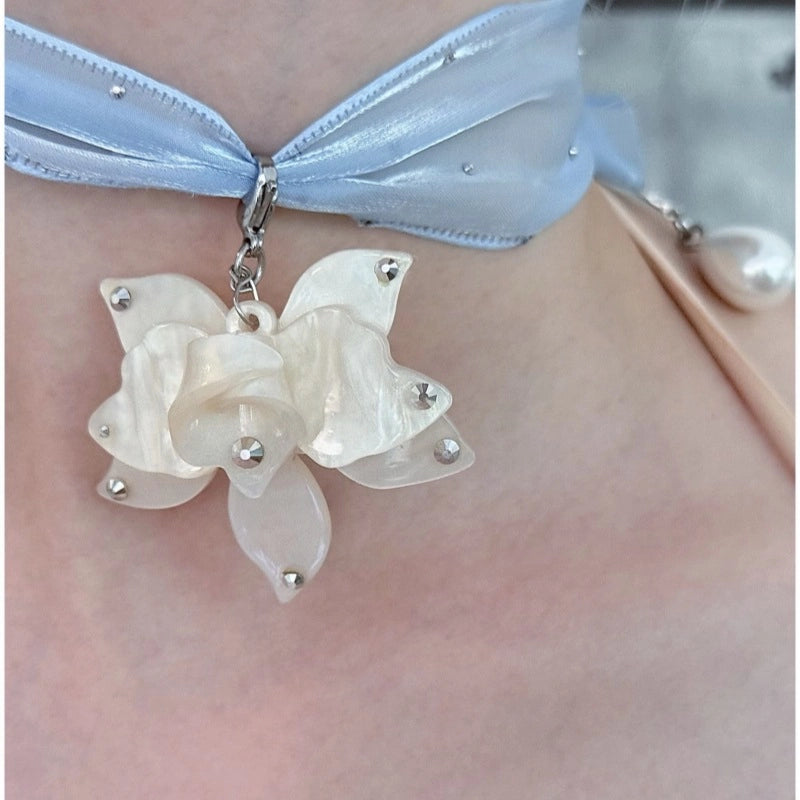 Collana girocollo di alta gamma dal design ricercato, con nastro lungo a pois e strass, pendente a forma di fiore e perle.