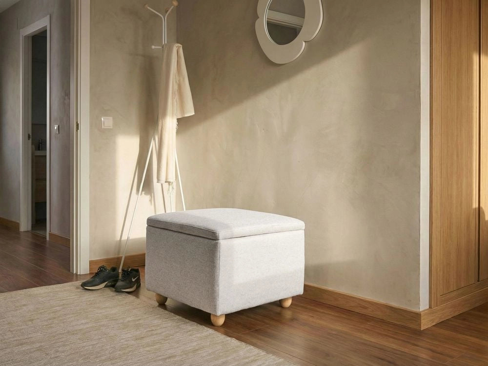 Pouf contenitore in tessuto grigio chiaro con finitura idrorepellente. Poggiapiedi imbottito con contenitore e seduta per ingresso.