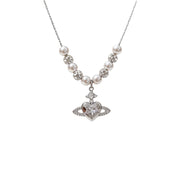 Collana con pianeta a forma di cuore in zircone, ciondolo di Saturno e catena di perle per la clavicola.