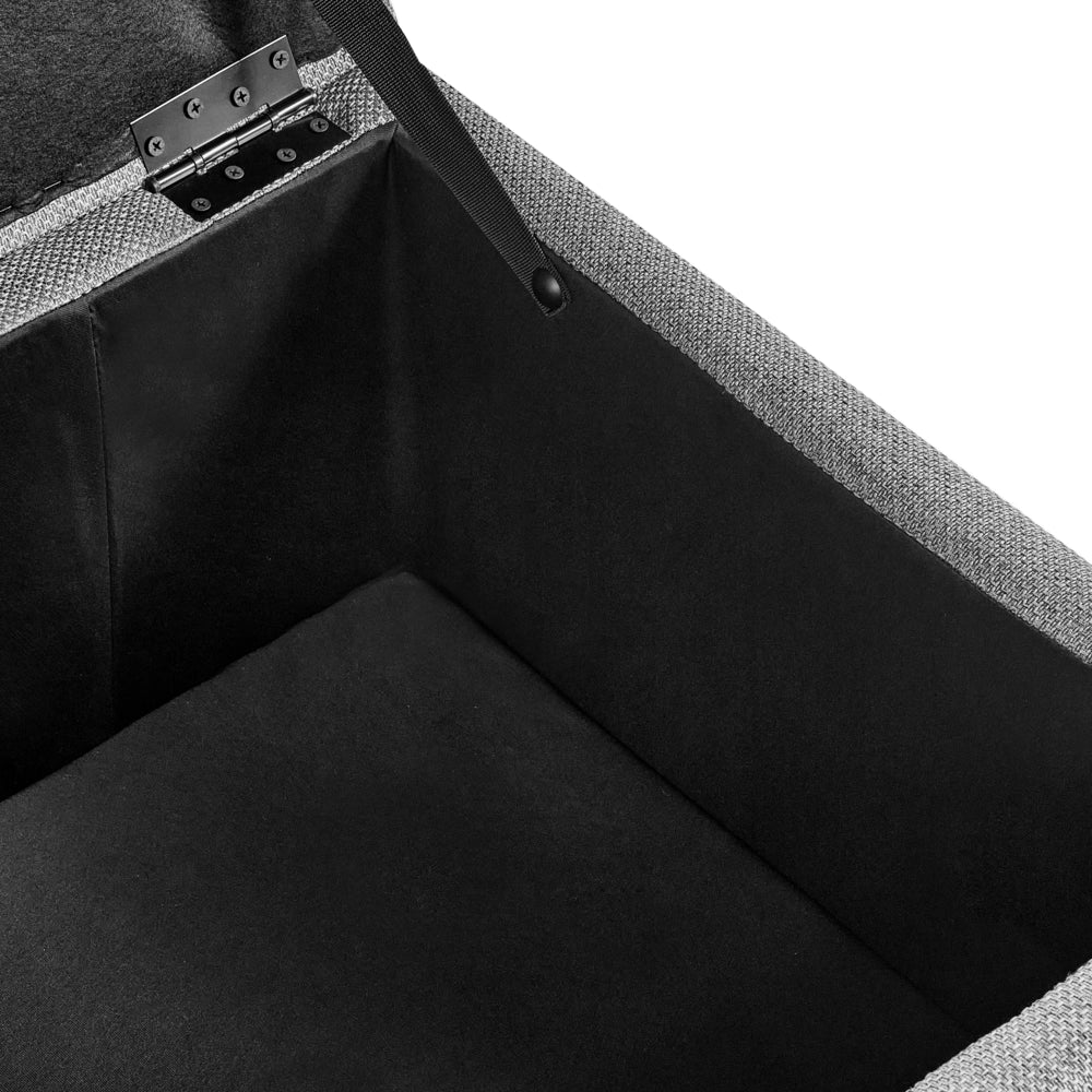 Pouf contenitore in tessuto grigio chiaro con finitura idrorepellente. Poggiapiedi imbottito con contenitore e seduta per ingresso.
