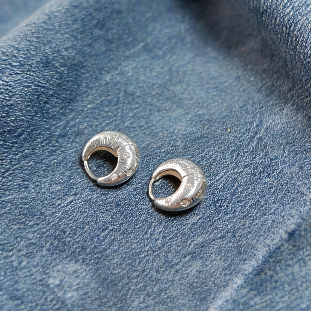 Orecchini irregolari in metallo spazzolato con zirconi a forma di stella.
