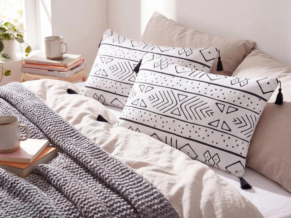 Set di 2 cuscini motivo geometrico nappe 30 x 50cm bianco e nero