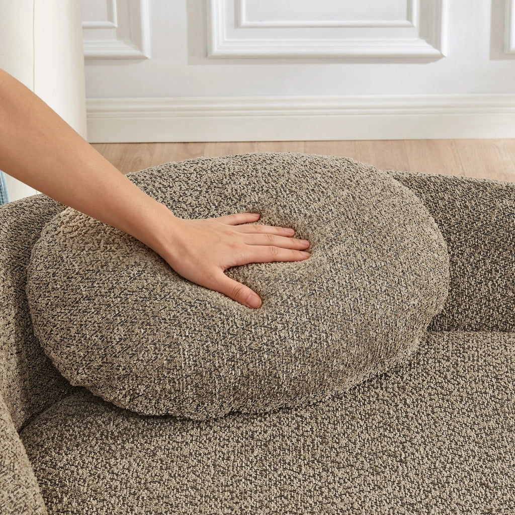 Divano minimalista in tessuto Teddy marrone con design arrotondato e cuscino di supporto