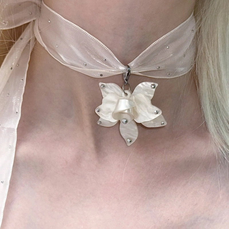 Collana girocollo di alta gamma dal design ricercato, con nastro lungo a pois e strass, pendente a forma di fiore e perle.