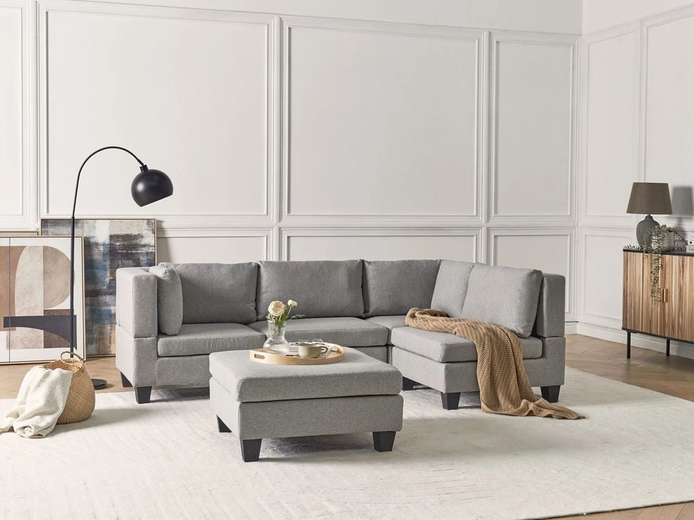 Divano componibile 4 posti imbottito in tessuto grigio chiaro con gambe nere schienale imbottito lato sinistro con pouf stile moderno