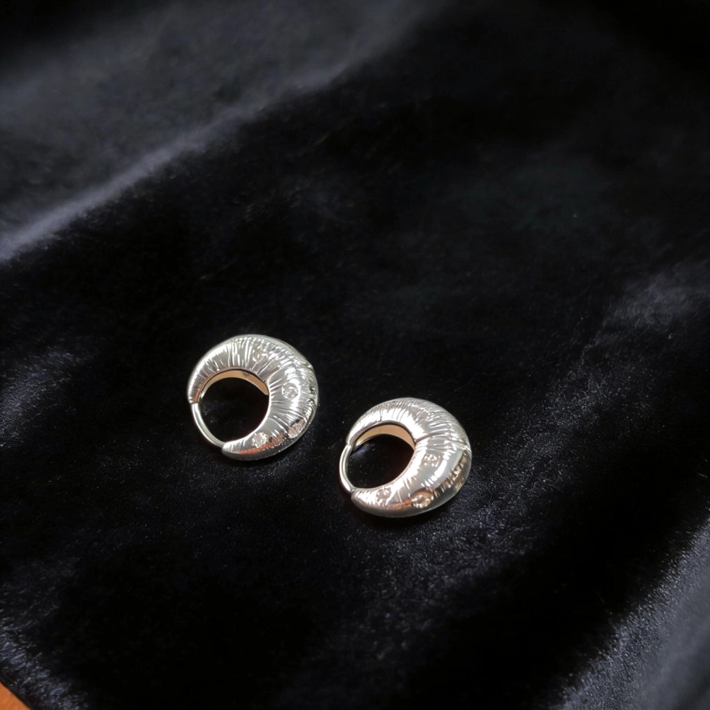 Orecchini irregolari in metallo spazzolato con zirconi a forma di stella.
