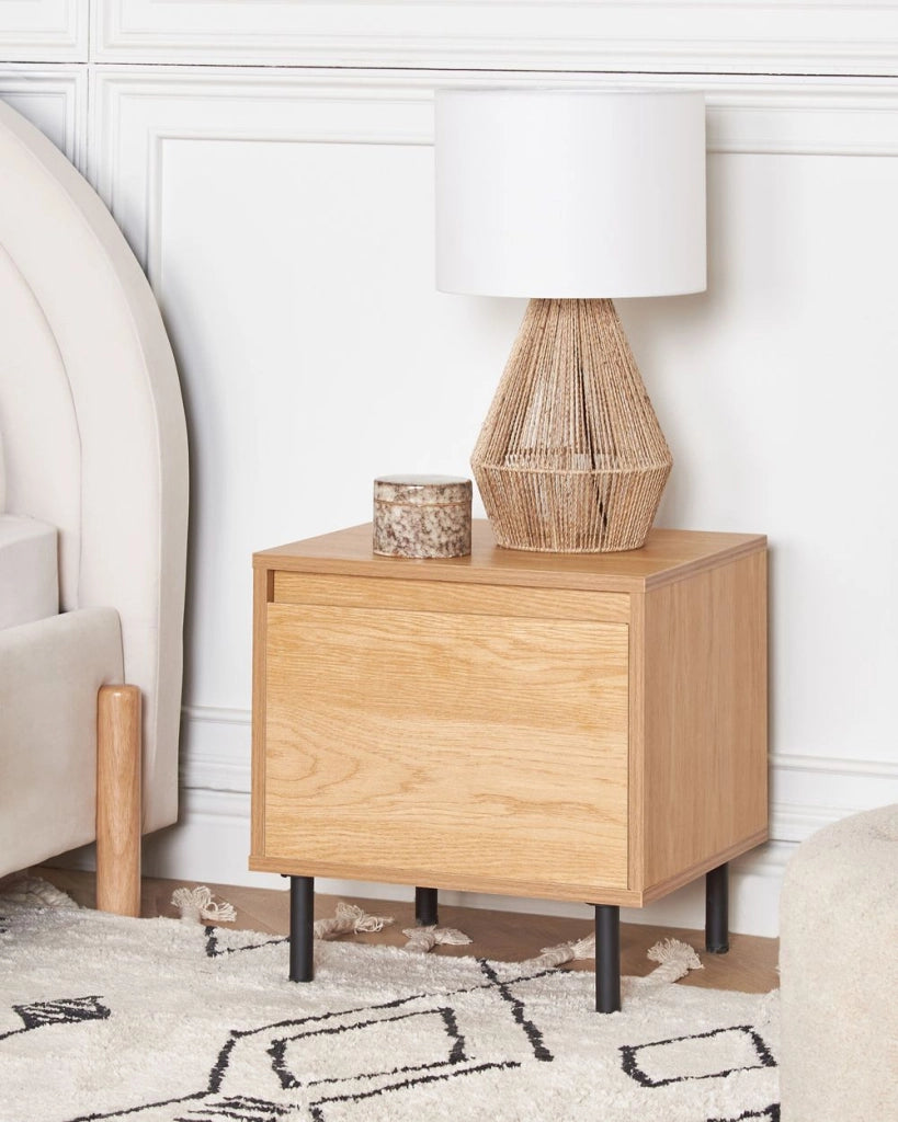 Comodino in truciolato di legno chiaro con 1 cassetto in metallo con gambe nere, minimalista e contemporaneo.