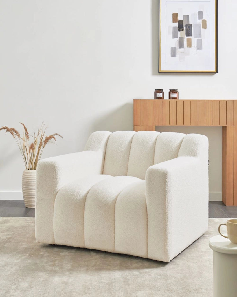 Poltrona con rivestimento in bouclé bianco avorio schienale imbottito e cuscini spessi perfetta per un soggiorno moderno
