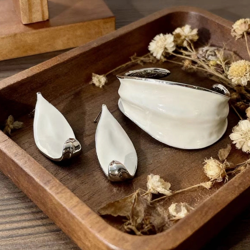 Bracciale e orecchini in smalto bianco a forma di voluta: gioielli di nicchia, minimalisti e di alta gamma per donna.