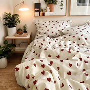 Set da letto romantico con coperta a cuore rosso, insieme a lenzuolo e cuscino.