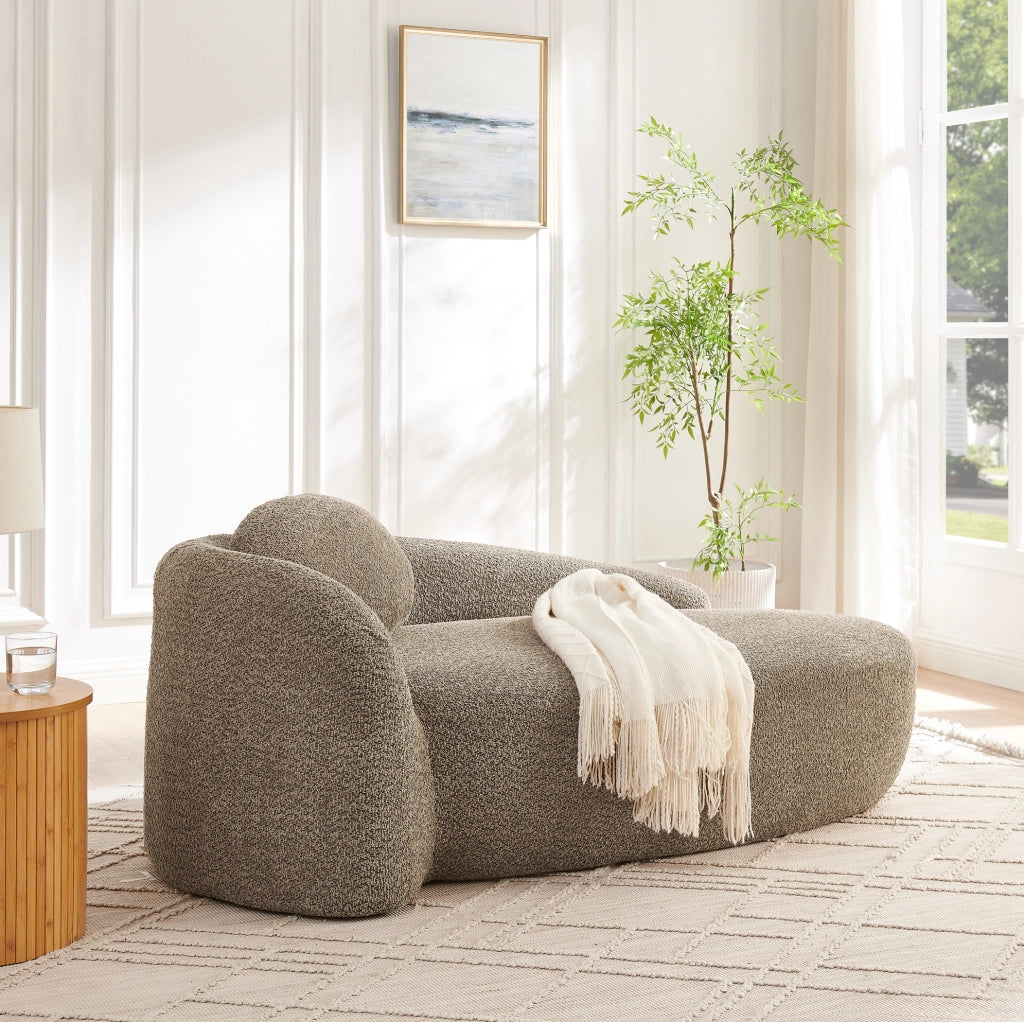 Divano minimalista in tessuto Teddy marrone con design arrotondato e cuscino di supporto