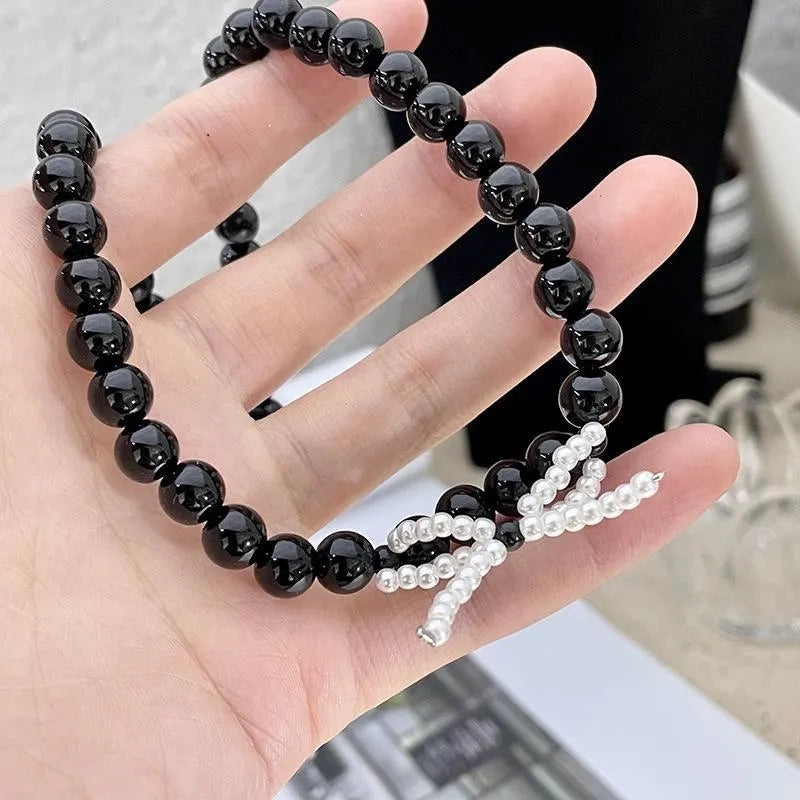 Collana con fiocco in corda nera e perline: regalo fatto a mano per donna.