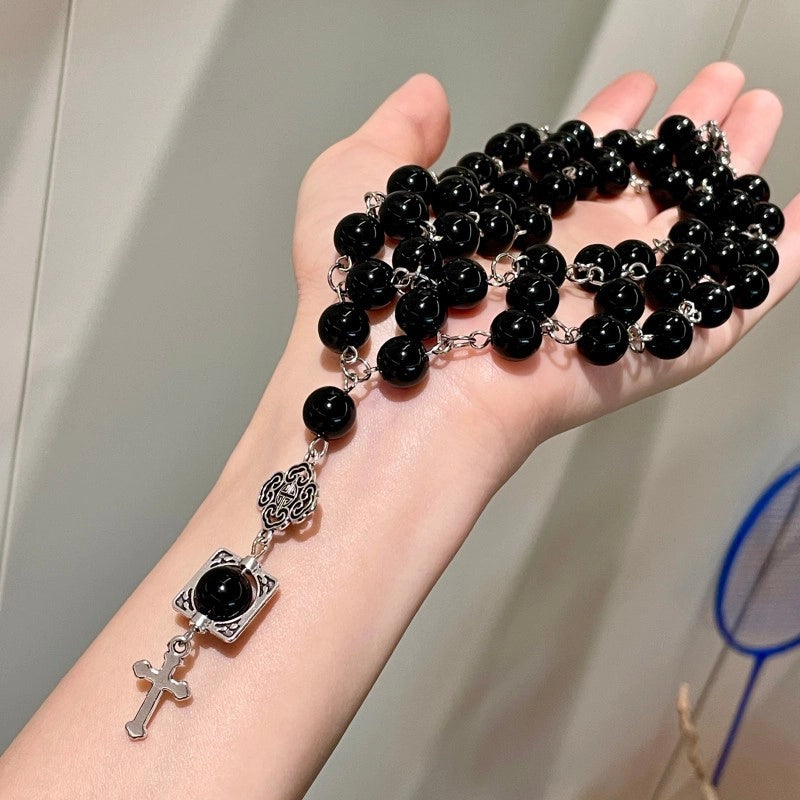 Collana a catena a tre strati con perline di cristallo nero e ciondolo a croce, ideale da portare lungo la clavicola.