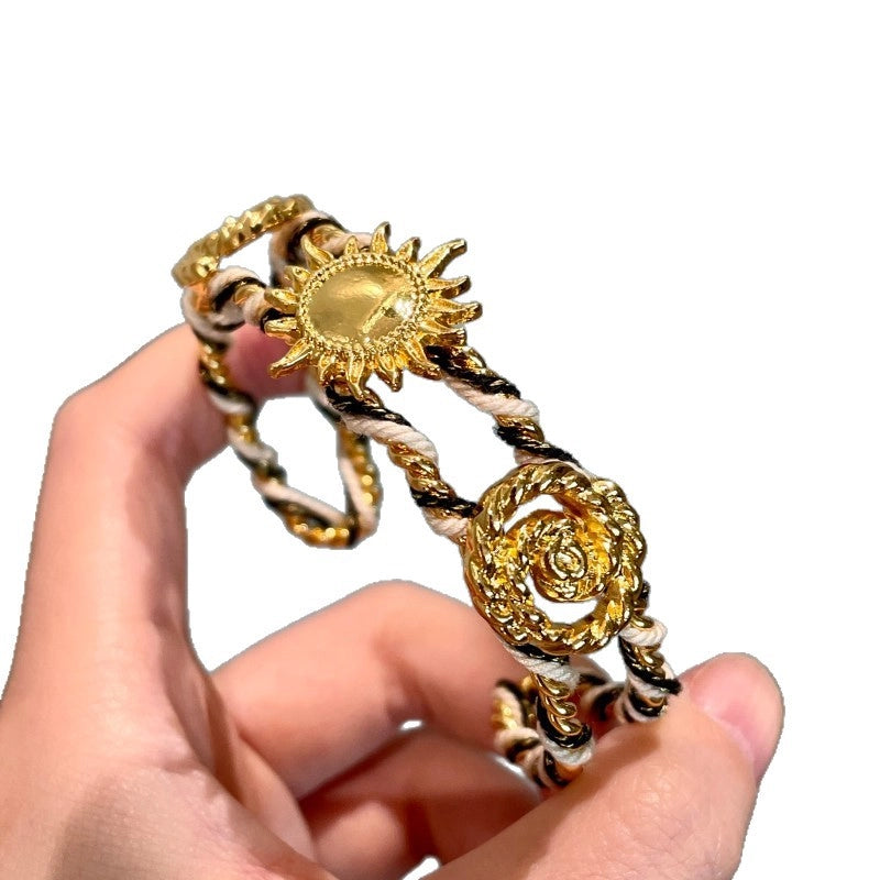 Bracciale regolabile da donna con girasoli in metallo traforato e intrecciato a mano.