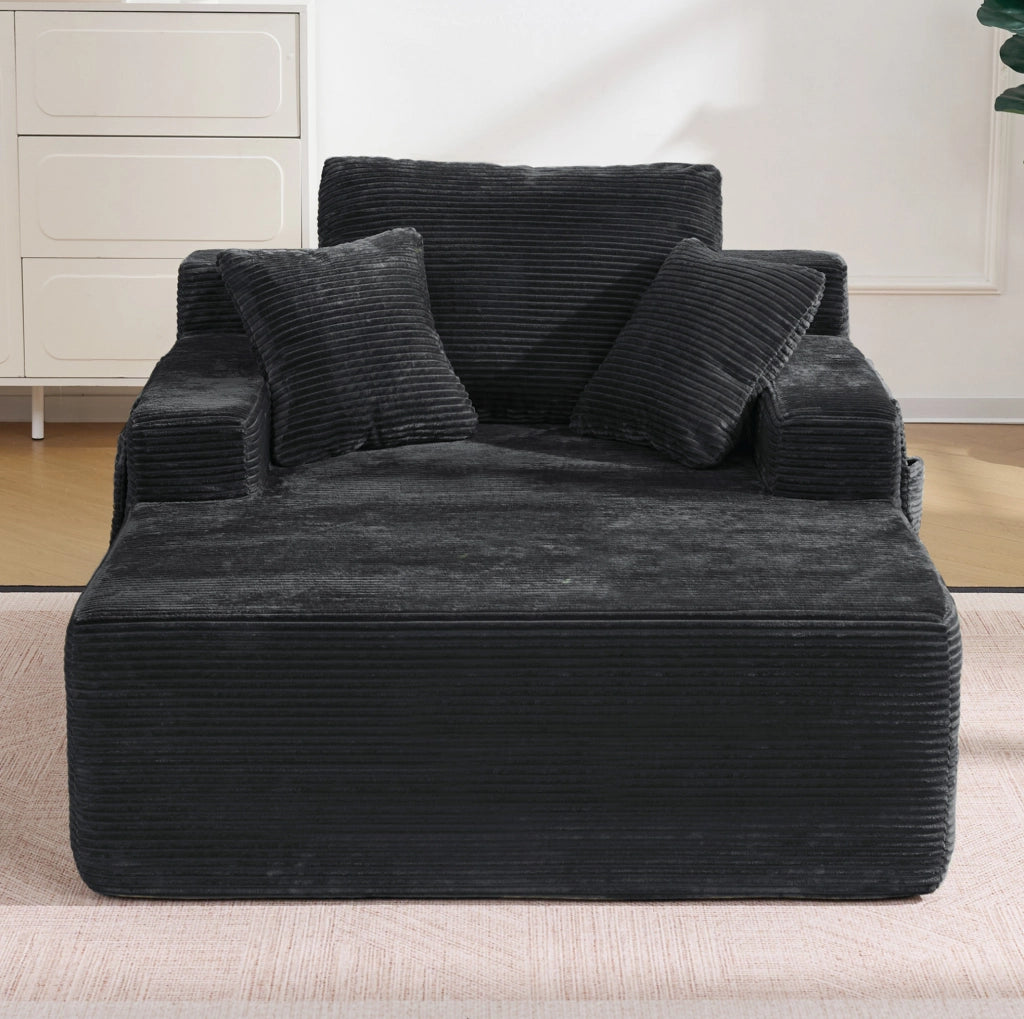 Divano compatto in corduroy nero con tasche laterali e cuscini decorativi
