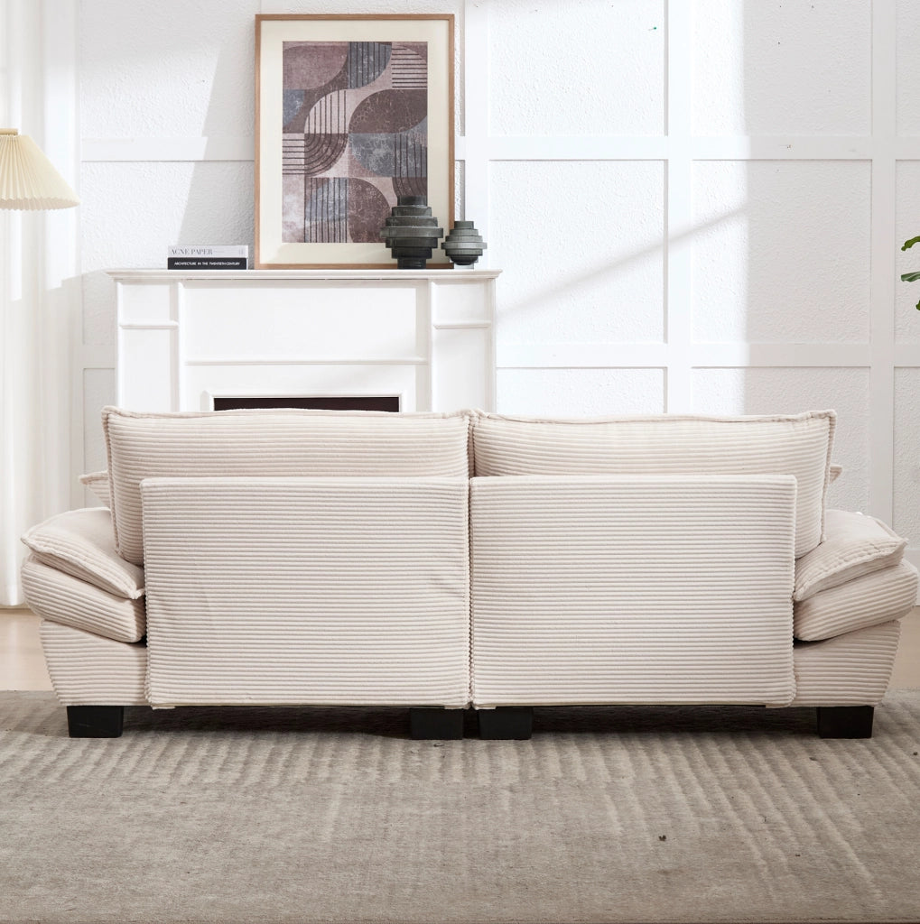 Divano imbottito in velluto beige con seduta profonda, cuscini e braccioli per il relax