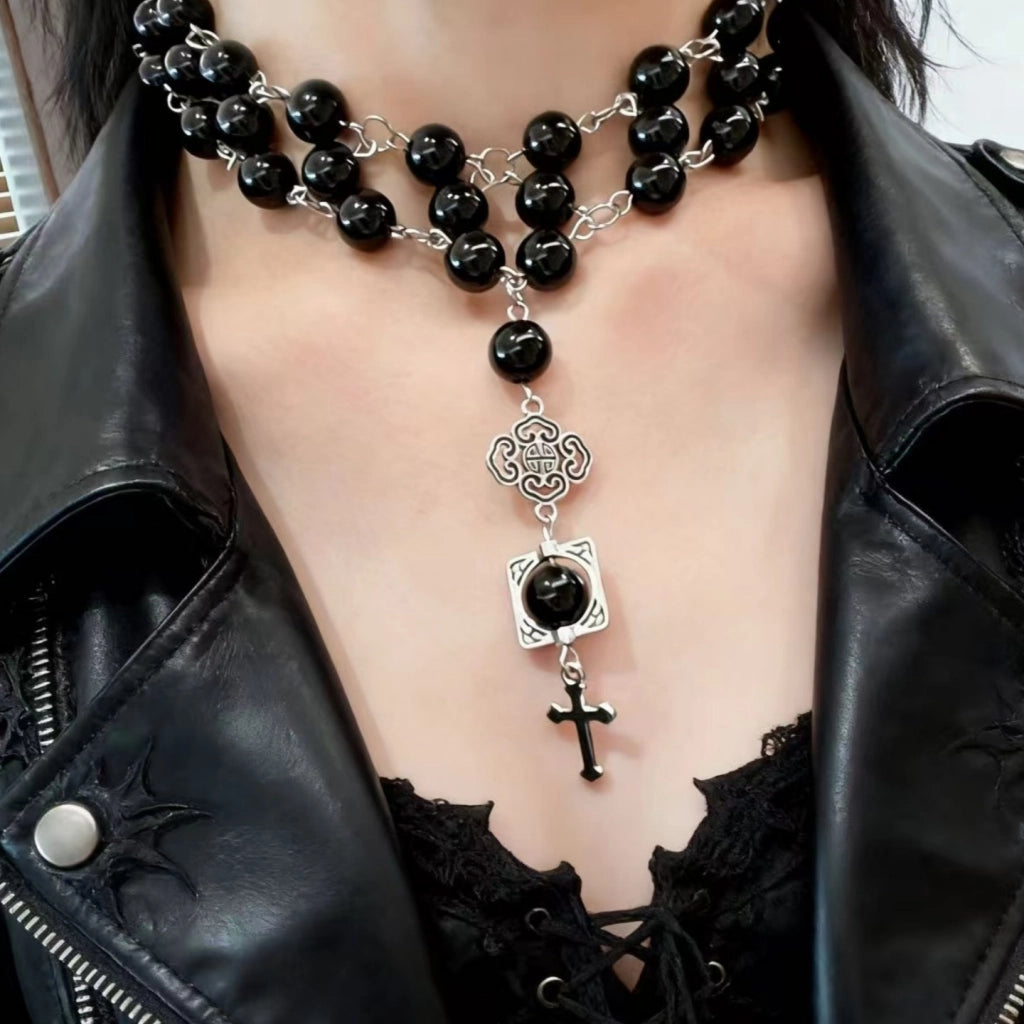 Collana a catena a tre strati con perline di cristallo nero e ciondolo a croce, ideale da portare lungo la clavicola.