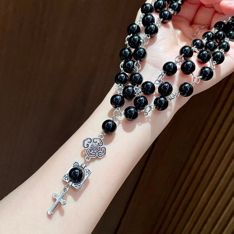 Collana a catena a tre strati con perline di cristallo nero e ciondolo a croce, ideale da portare lungo la clavicola.
