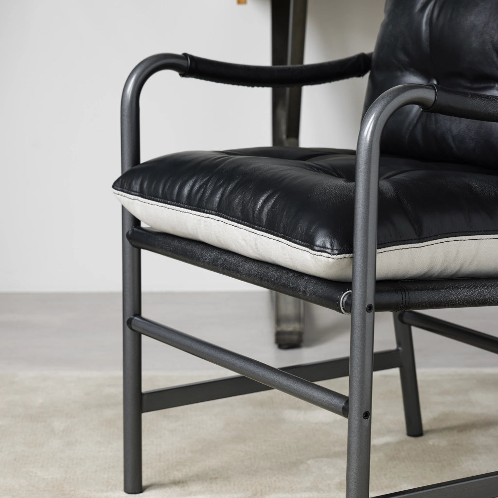 Poltrona in pelle stile mid century moderno con struttura in metallo nero, seduta ampia e braccioli, nera
