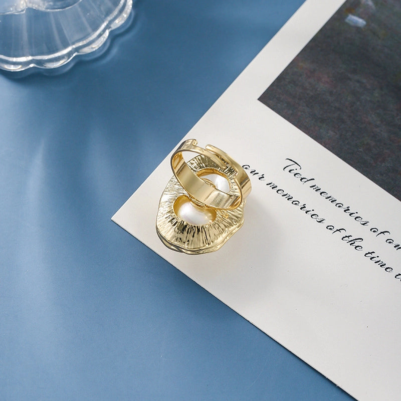 Un anello metallico unico ed esagerato, con un'apertura semplice e dalla forma irregolare e una perla incastonata sull'indice.
