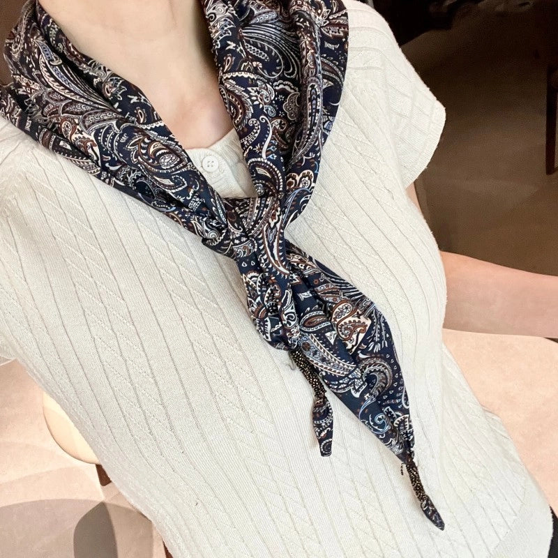 Cintura decorata con sciarpa paisley blu scuro abbinata a pantaloni, jeans e gonna, sovrapposta a una sciarpa triangolare e a una patta posteriore.