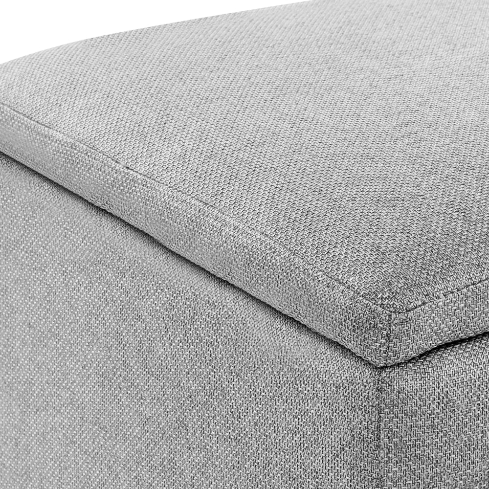 Pouf contenitore in tessuto grigio chiaro con finitura idrorepellente. Poggiapiedi imbottito con contenitore e seduta per ingresso.