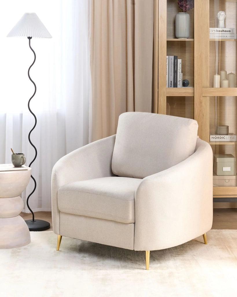 Poltrona in tessuto bouclè beige chiaro con gambe curve dorate e seduta morbida stile glamour elegante salotto