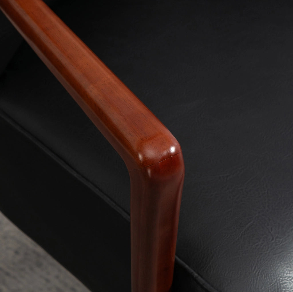 Poltroncina imbottita nera con braccioli e gambe in legno