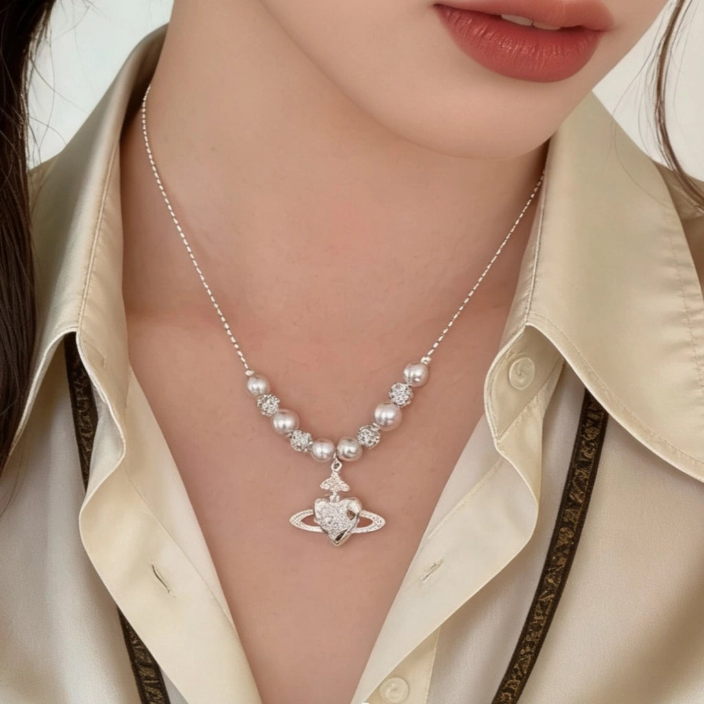 Collana con pianeta a forma di cuore in zircone, ciondolo di Saturno e catena di perle per la clavicola.