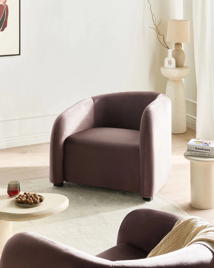 Poltrona elegante e moderna in velluto con schienale curvo e braccioli imbottiti rivestita in velluto marrone scuro