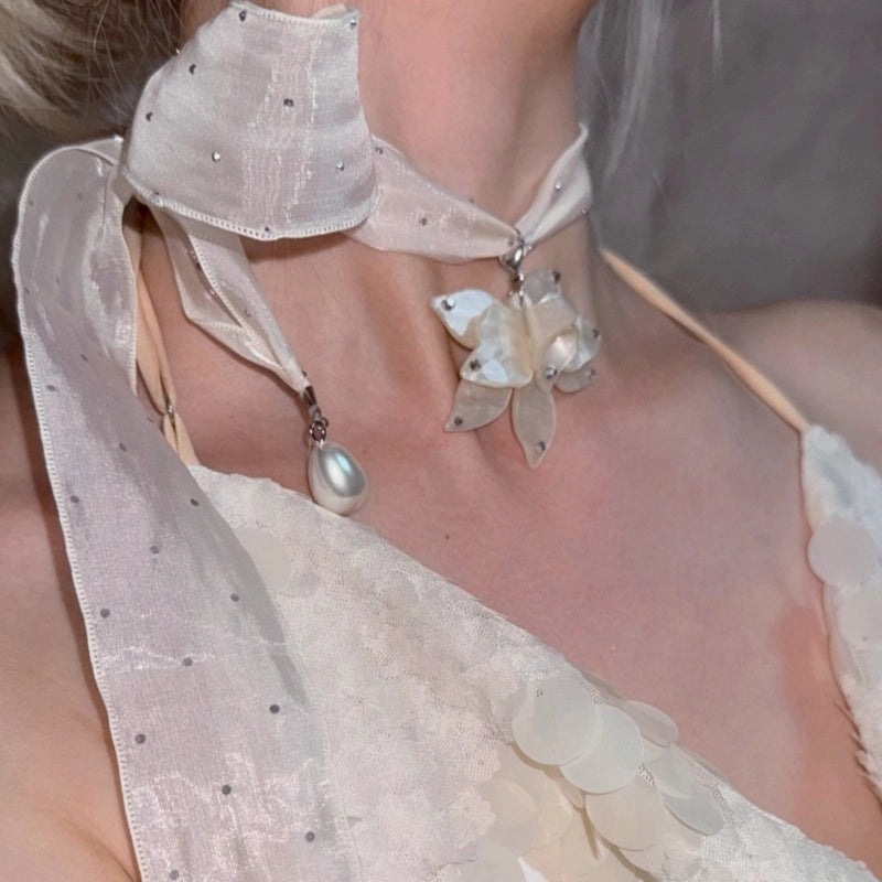 Collana girocollo di alta gamma dal design ricercato, con nastro lungo a pois e strass, pendente a forma di fiore e perle.