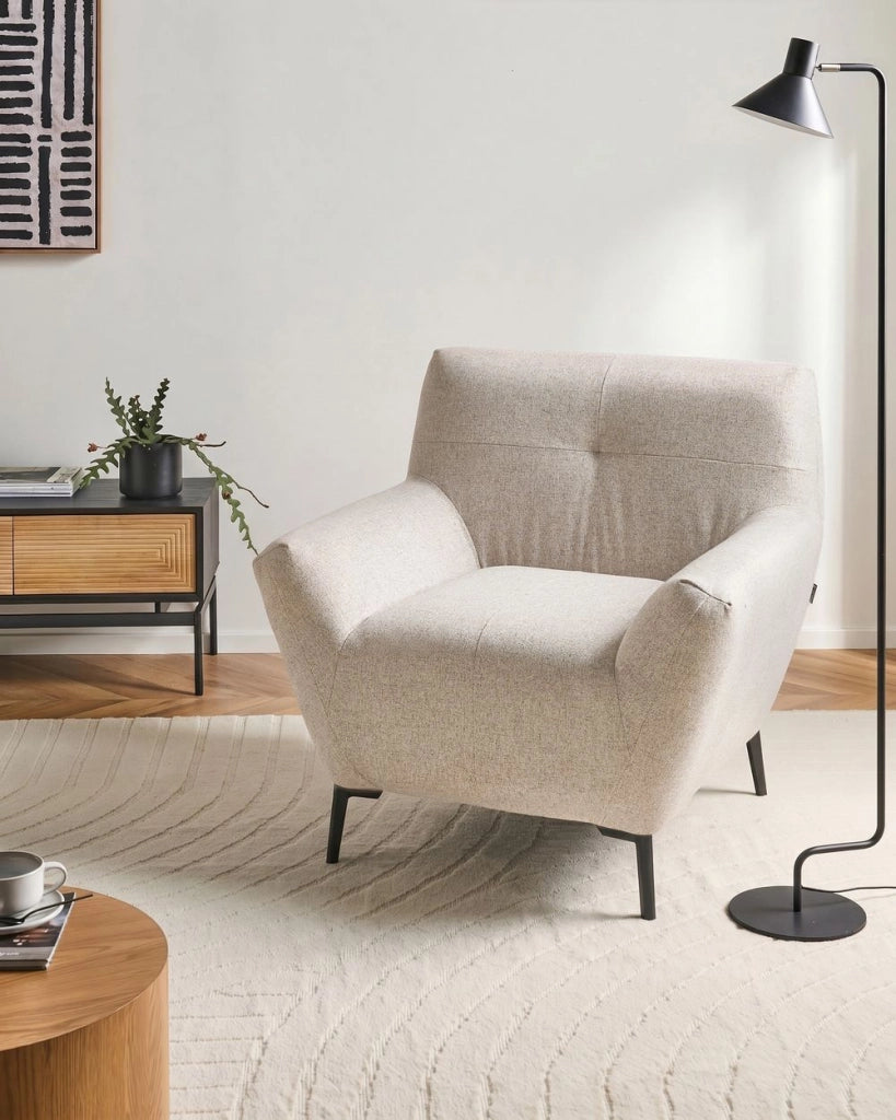 Poltrona in tessuto beige con braccioli, trapuntatura decorativa e gambe in metallo nero angolo lettura moderno per il soggiorno