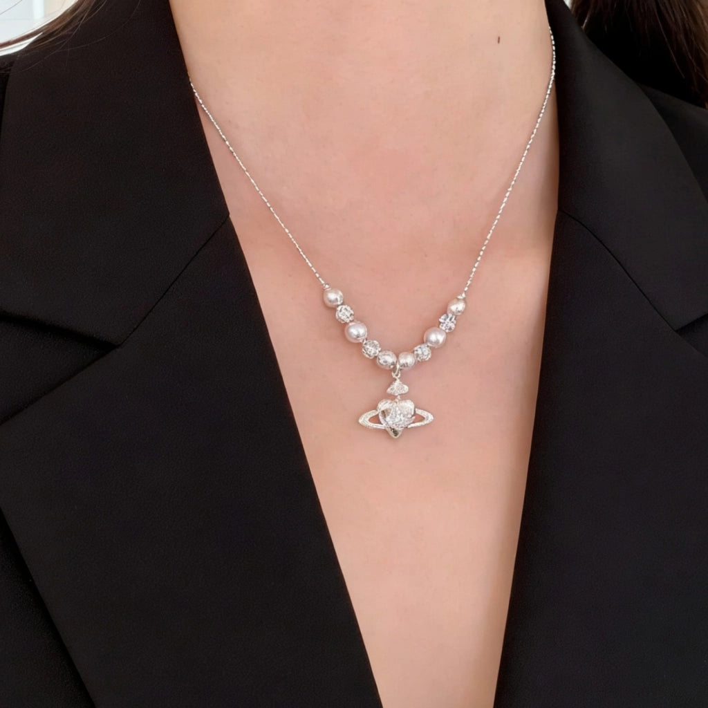 Collana con pianeta a forma di cuore in zircone, ciondolo di Saturno e catena di perle per la clavicola.