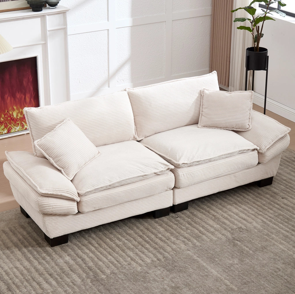 Divano imbottito in velluto beige con seduta profonda, cuscini e braccioli per il relax