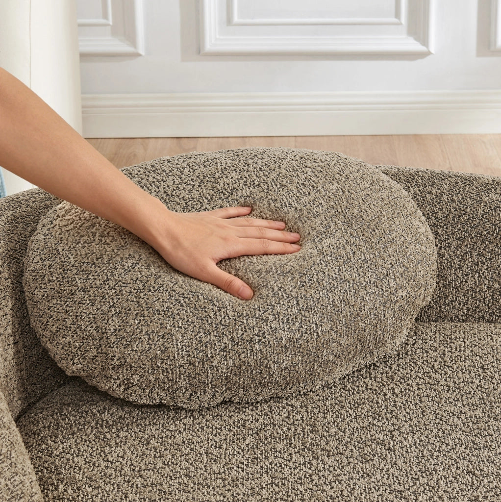 Divano minimalista in tessuto Teddy marrone con design arrotondato e cuscino di supporto