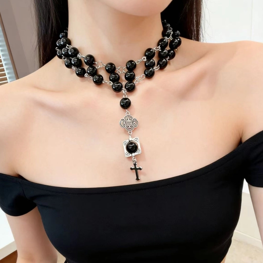 Collana a catena a tre strati con perline di cristallo nero e ciondolo a croce, ideale da portare lungo la clavicola.