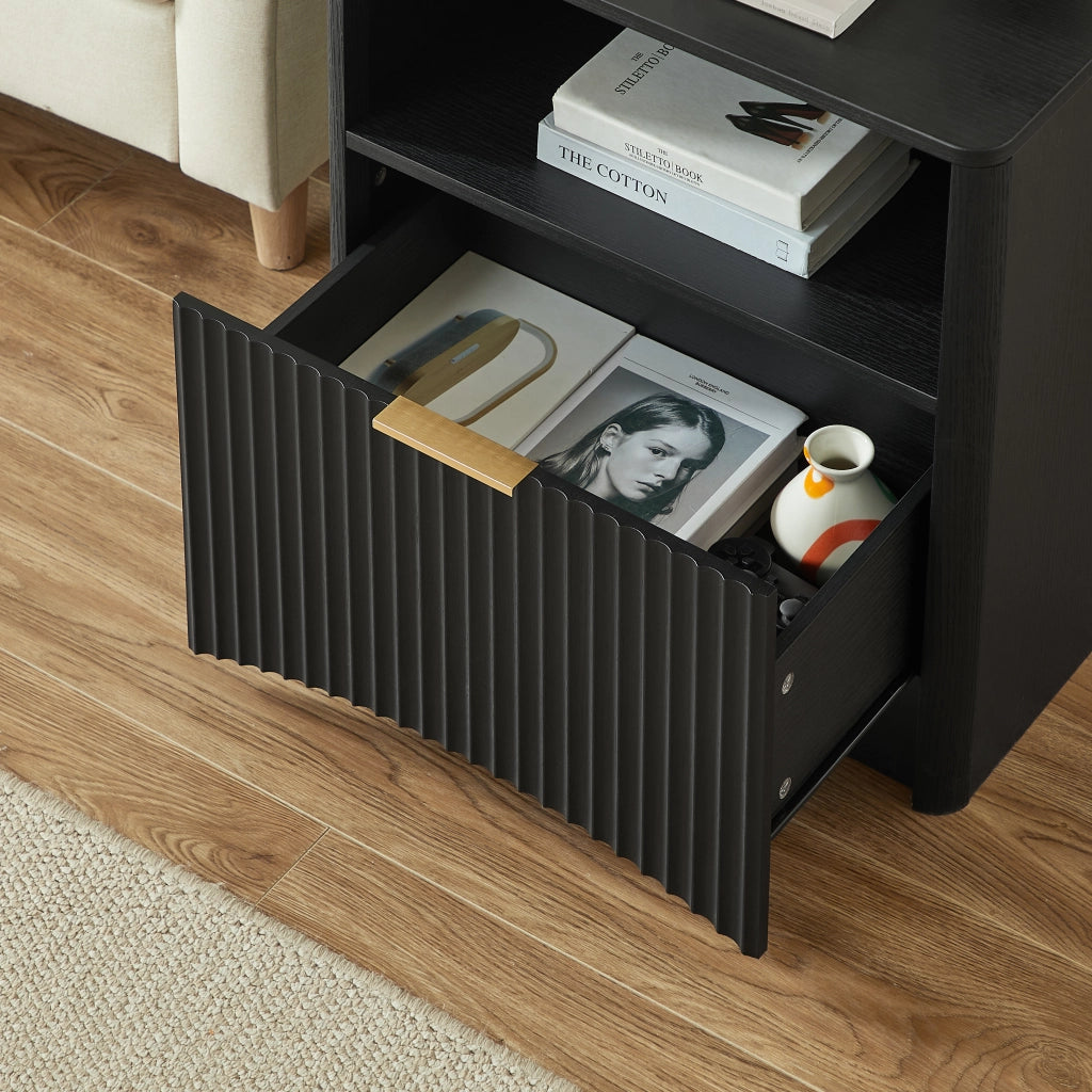 Comodino moderno in truciolare nero con cassetto aperto, maniglia dorata e design scanalato