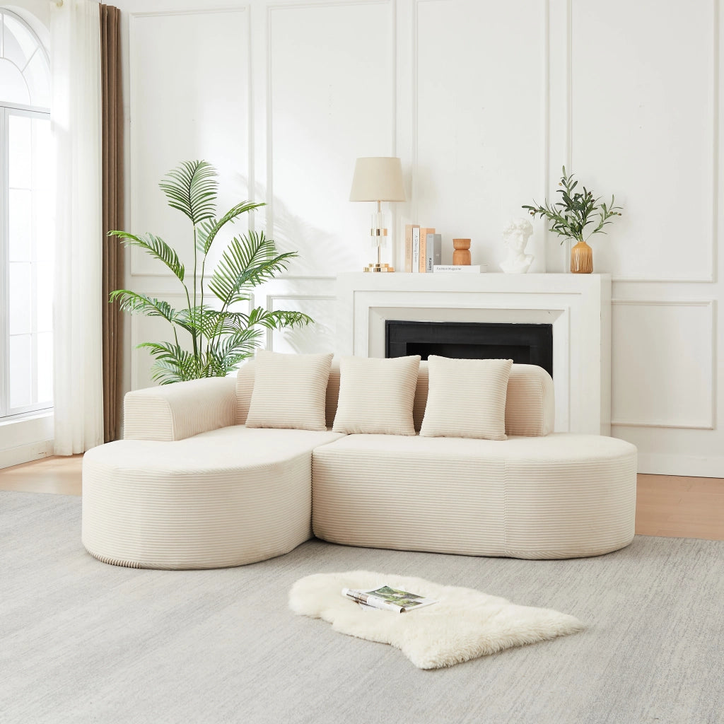 Divano angolare a L con chaise longue; braccioli curvi e cuscini in velluto a coste beige