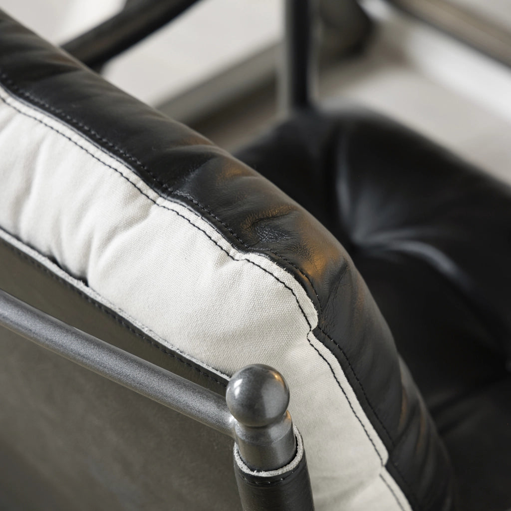Poltrona in pelle stile mid century moderno con struttura in metallo nero, seduta ampia e braccioli, nera
