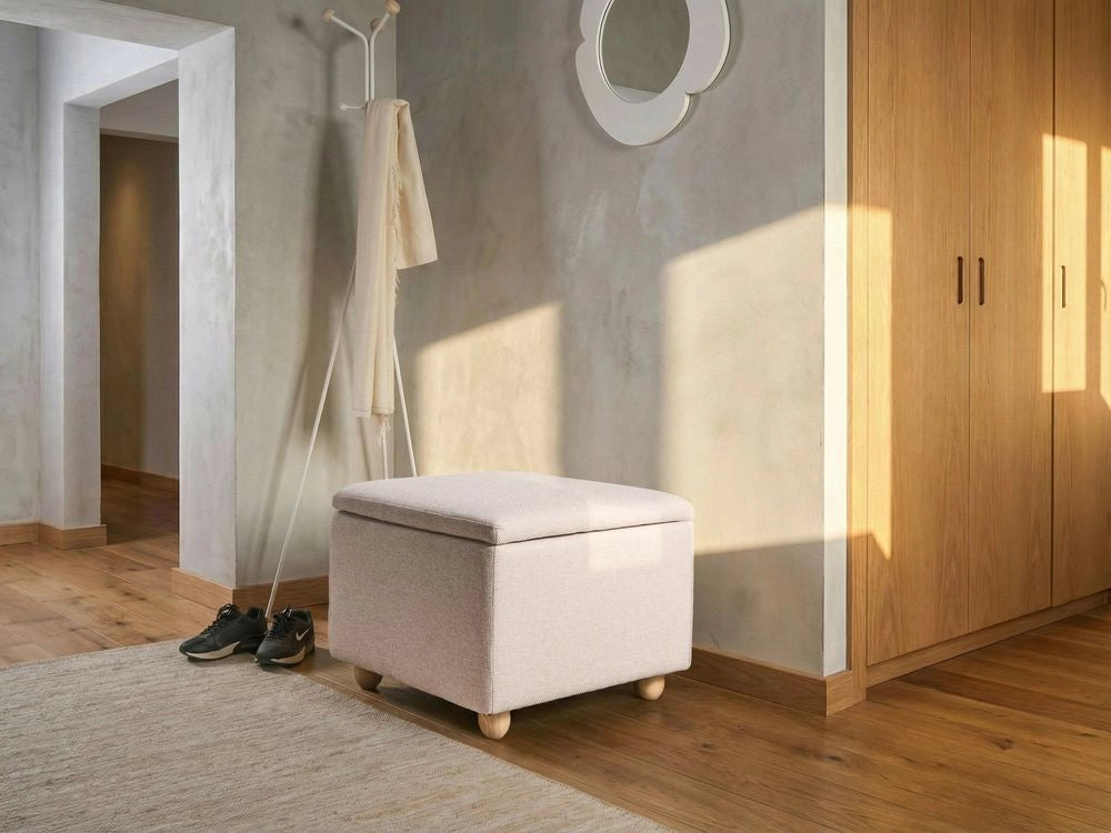 Pouf contenitore in tessuto beige con finitura idrorepellente. Poggiapiedi imbottito con contenitore e seduta per ingresso.