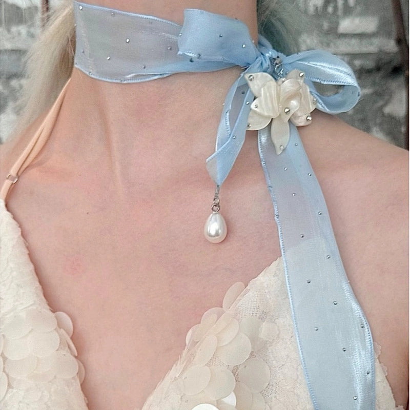 Collana girocollo di alta gamma dal design ricercato, con nastro lungo a pois e strass, pendente a forma di fiore e perle.